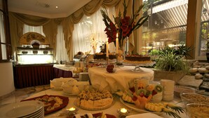 Ein reichhaltiges Buffet mit verschiedenen Speisen, einer Kuchenauslage und Kerzen auf dem Tisch.