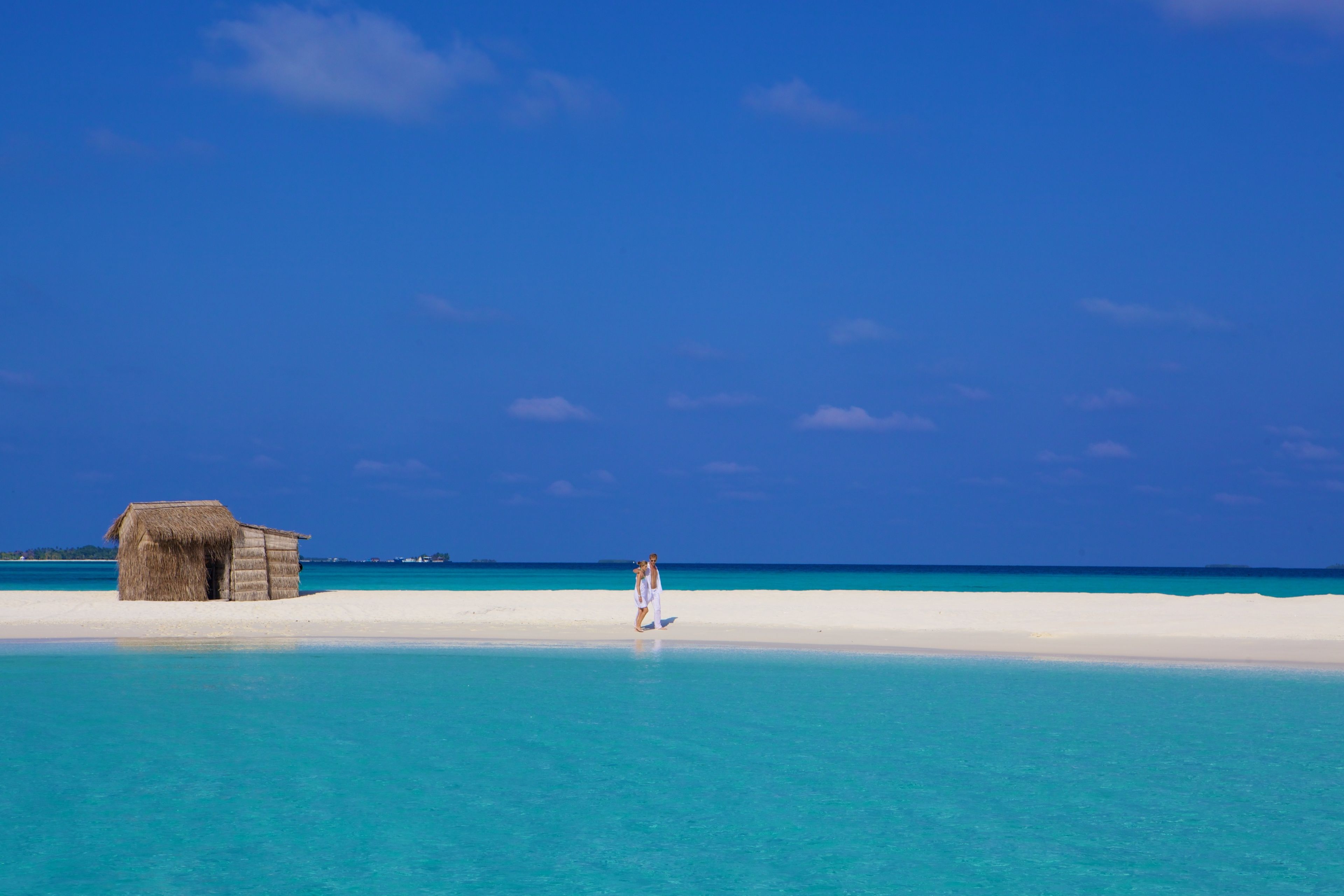 A beach with a hut and a person walking.