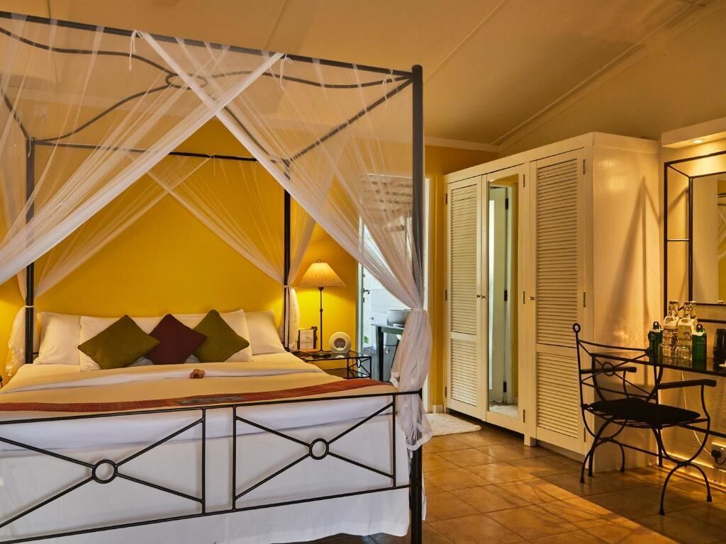 A bed with a canopy, a bedside table with a lamp, a chair, and a wardrobe.
