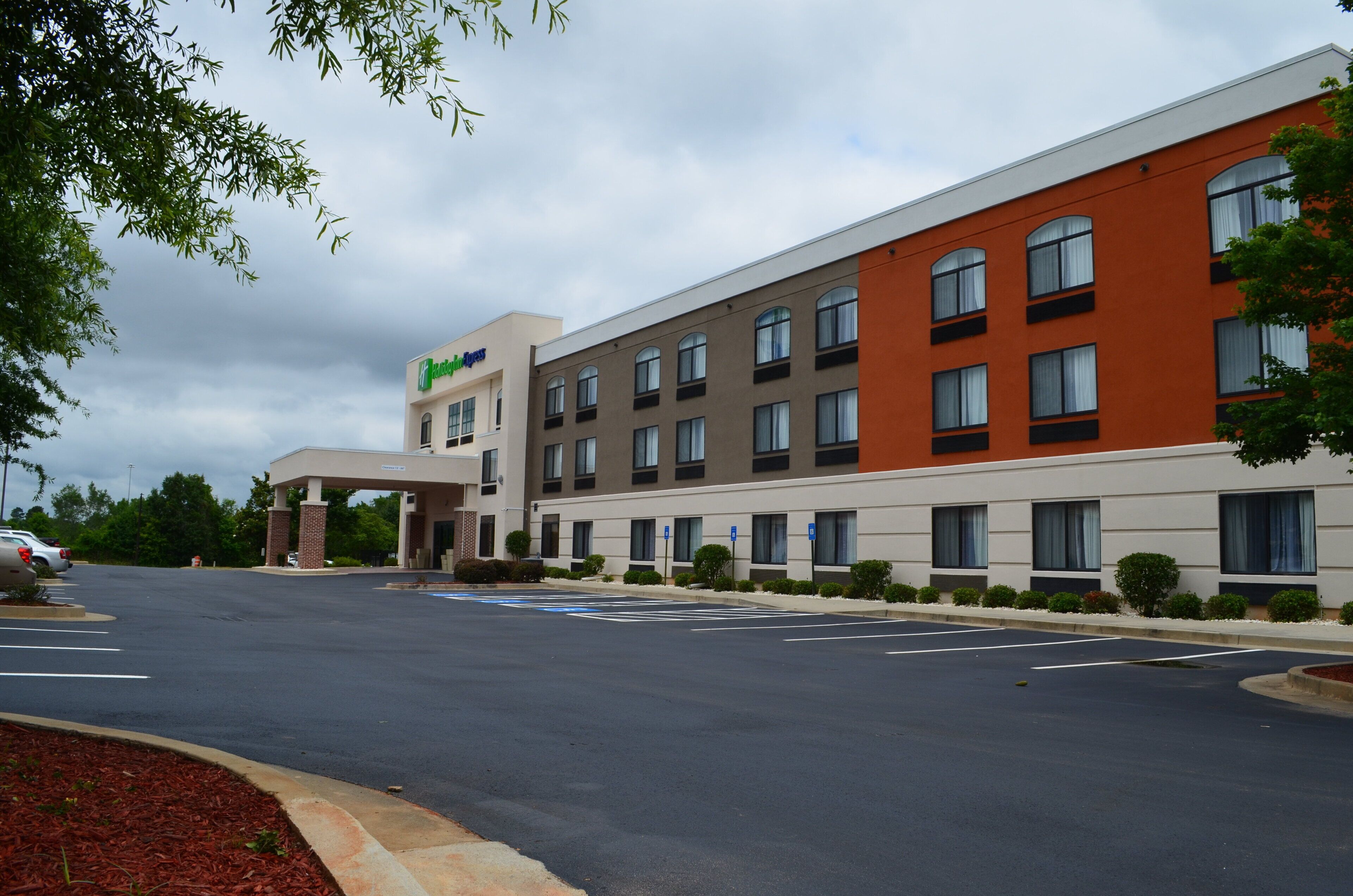 A hotel with a modern design, featuring a large parking lot and a covered entrance.