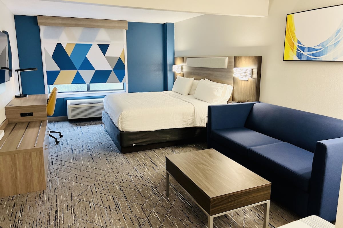 Ein Hotelzimmer mit Bett, Sofa, Schreibtisch und Stuhl.