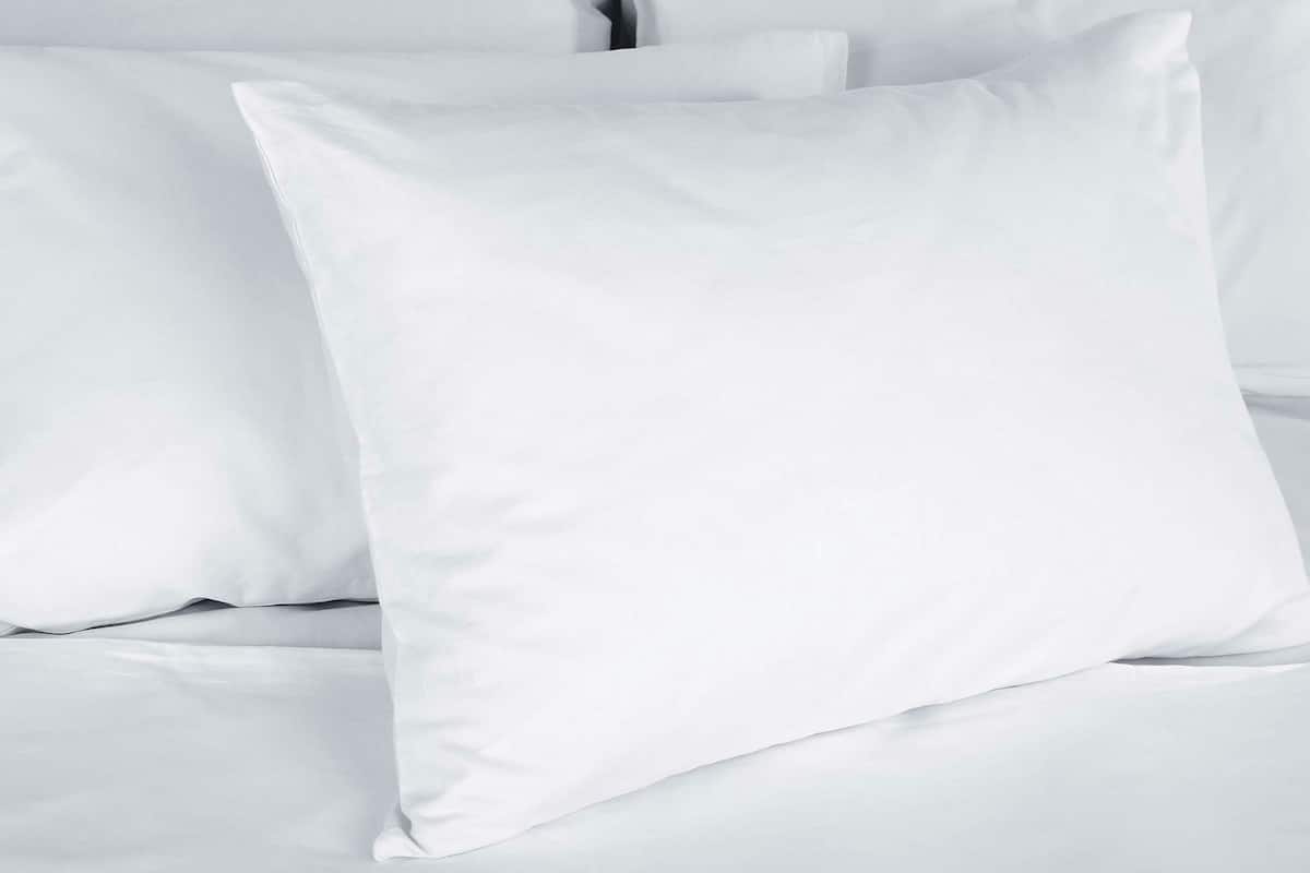 A bed with white bedding and pillows.