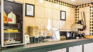 A kitchen area with a refrigerator, coffee machine, and various food items.