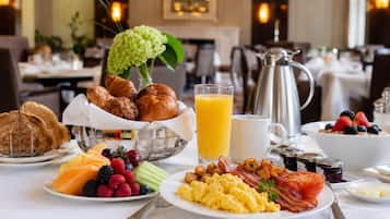A breakfast buffet with various food items, a pitcher of orange juice, and a coffee pot.