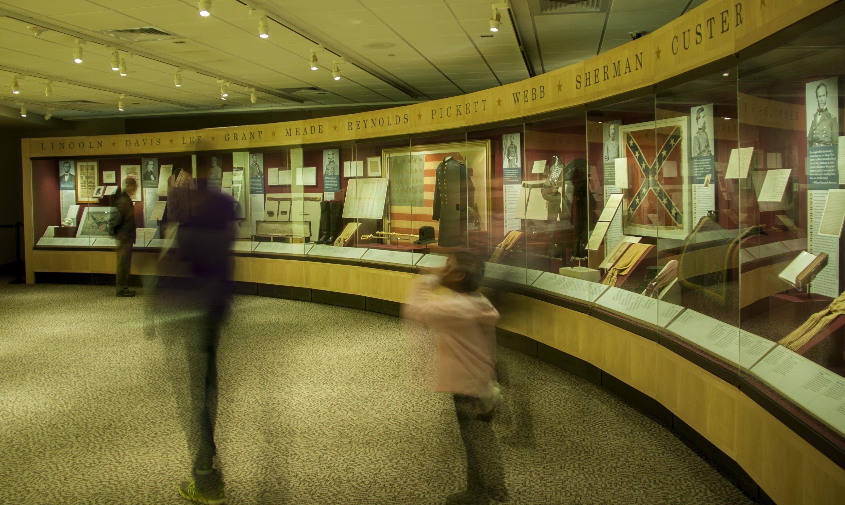 A museum exhibit with glass display cases containing historical artifacts and documents.