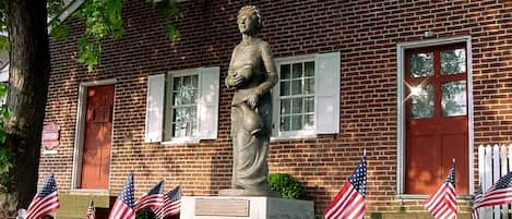 Un edificio de ladrillo con una estatua frente a él, rodeado de banderas estadounidenses.
