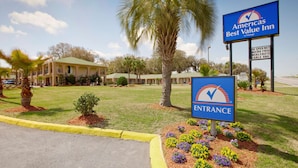 Ein Hotel Eingang mit einem Schild für Americas Best Value Inn, mit einer Palme und einem Gebäude mit mehreren Zimmern im Hintergrund.