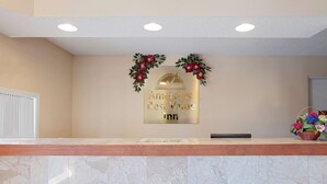 Ein Empfangsschalter mit Marmorplatte, eine Schilder mit der Aufschrift 'Americas Best Value Inn' und ein Blumenkranz darüber.