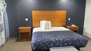 Ein Hotelzimmer mit einem Bett, Nachttischen, einer Bank und einem an der Wand befestigten Telefon.