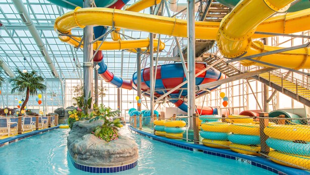An indoor water park with multiple water slides, a pool, and seating areas.