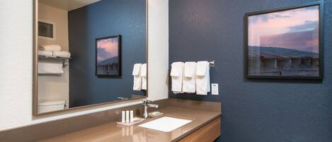Un baño moderno con un espejo grande, un lavamanos y dos cuadros en la pared.
