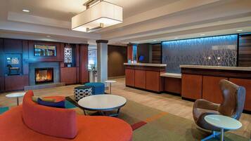 A modern lobby with a fireplace, seating areas, a reception desk, and a decorative wall.