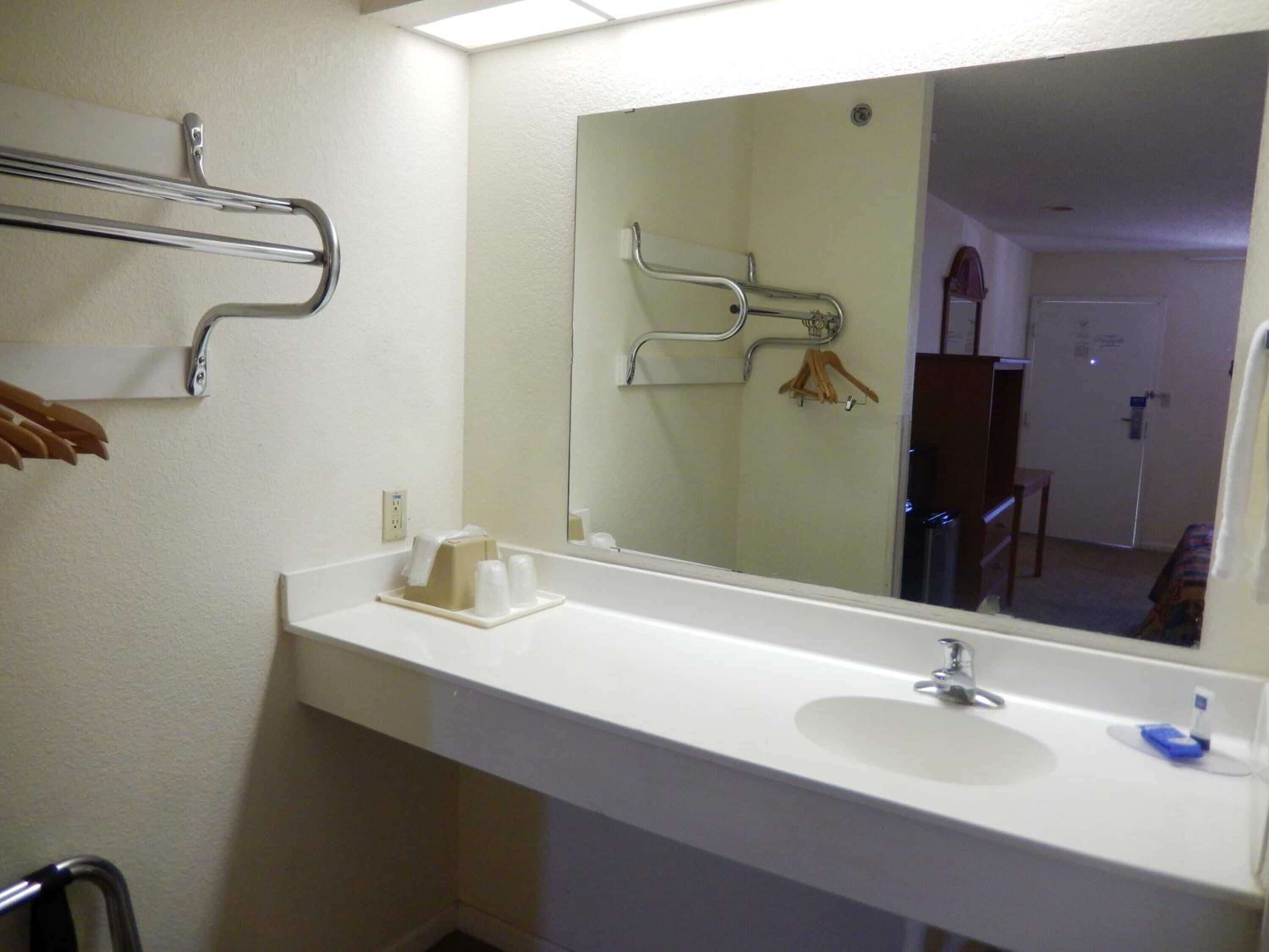 Une salle de bain avec un lavabo blanc, un miroir et un porte-serviettes.