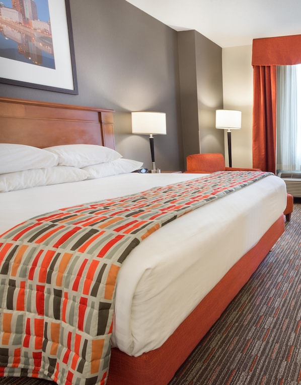 A hotel room with a large bed, two bedside lamps, a chair, and a framed picture on the wall. - Drury Inn & Suites Columbus Grove City (Grove City)