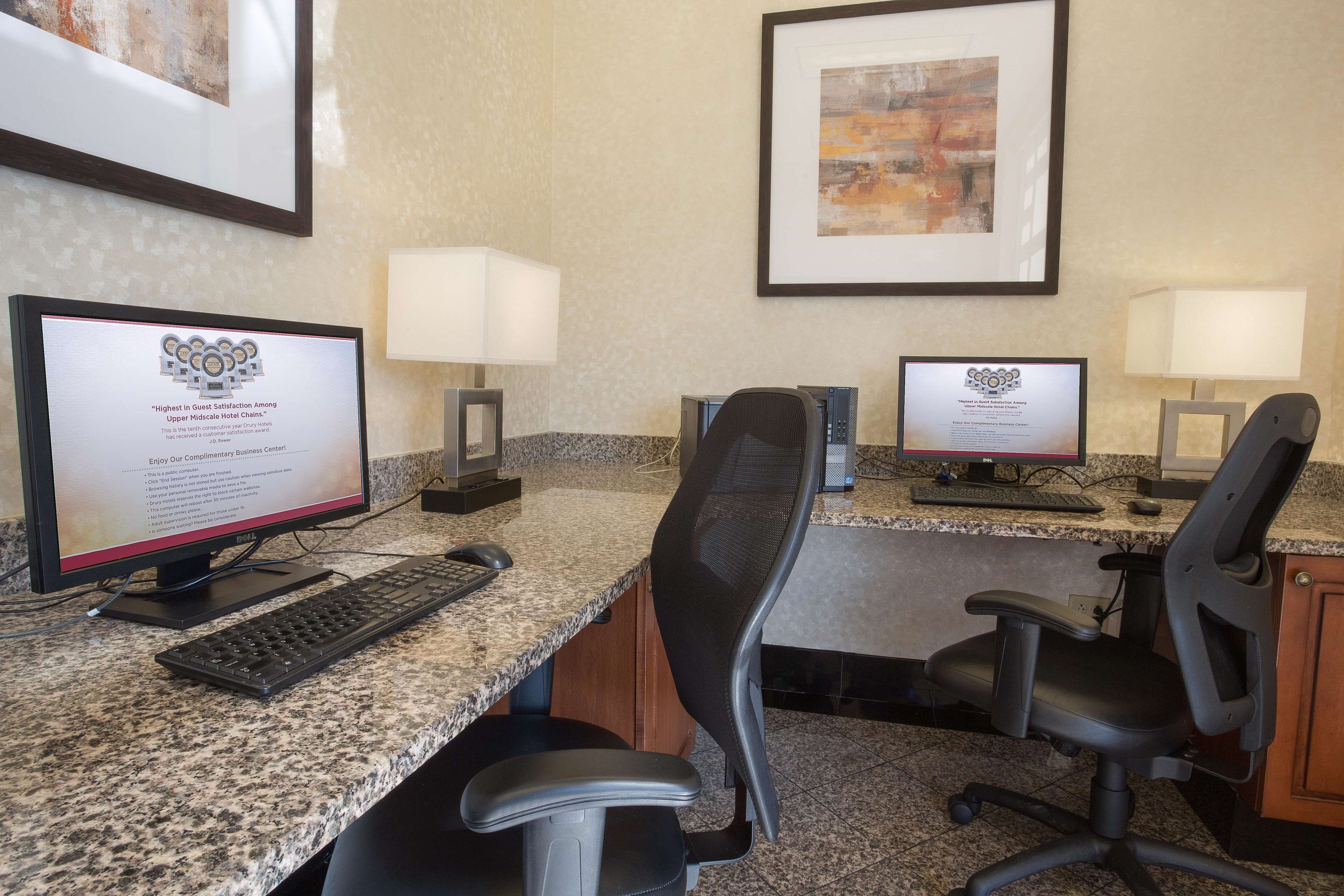 A hotel reception area with two computer workstations, each with a monitor displaying a guest satisfaction award.