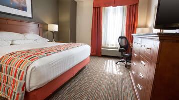 A hotel room with a bed, a desk, a chair, a television, and a window with curtains.