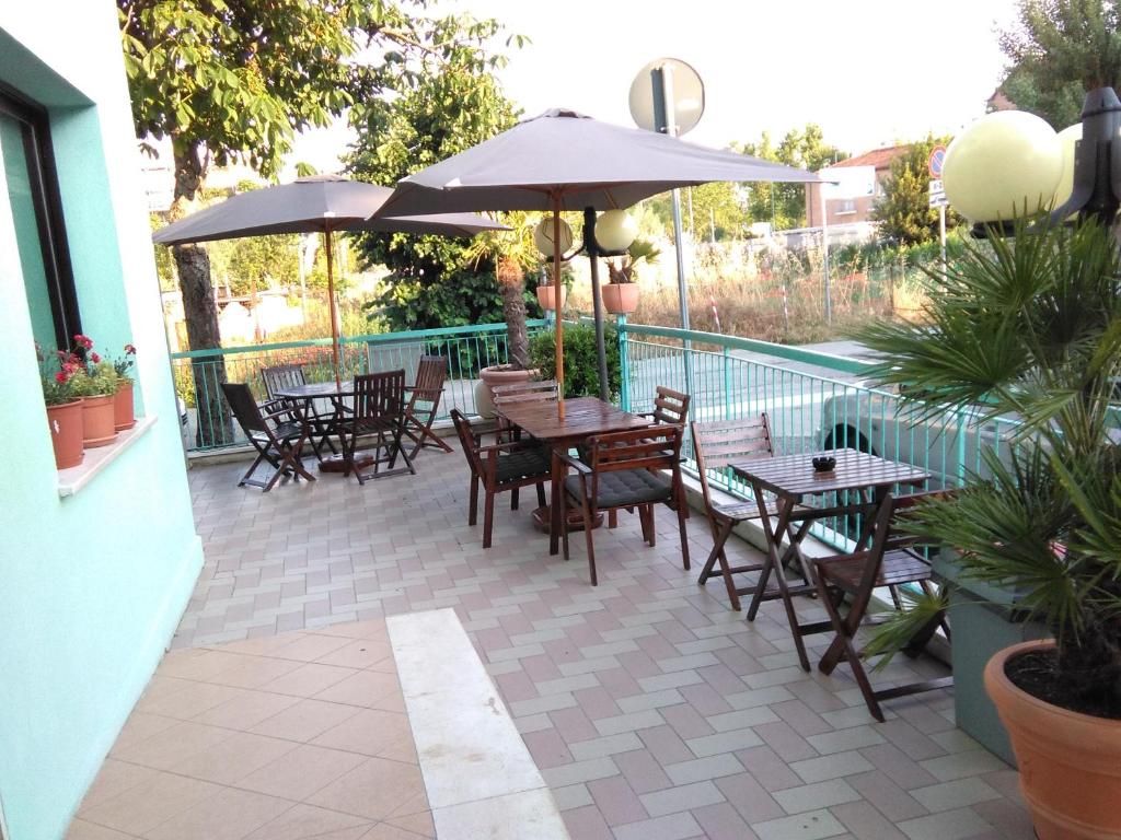 An outdoor patio area with tables and chairs, a large umbrella, and potted plants.