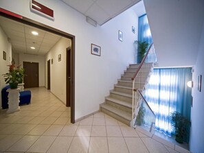 A hotel lobby with a staircase, tiled floor, and a reception desk. - Hotel Savina (Rimini)