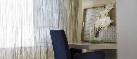 A modern dining area with a wooden table, two dark chairs, and a vase of white orchids.