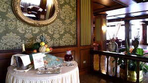 A room with a round mirror on the wall, a table with a 'Welcome Drink' sign, and a fruit basket. - Hotel Delle Palme (Lecce)
