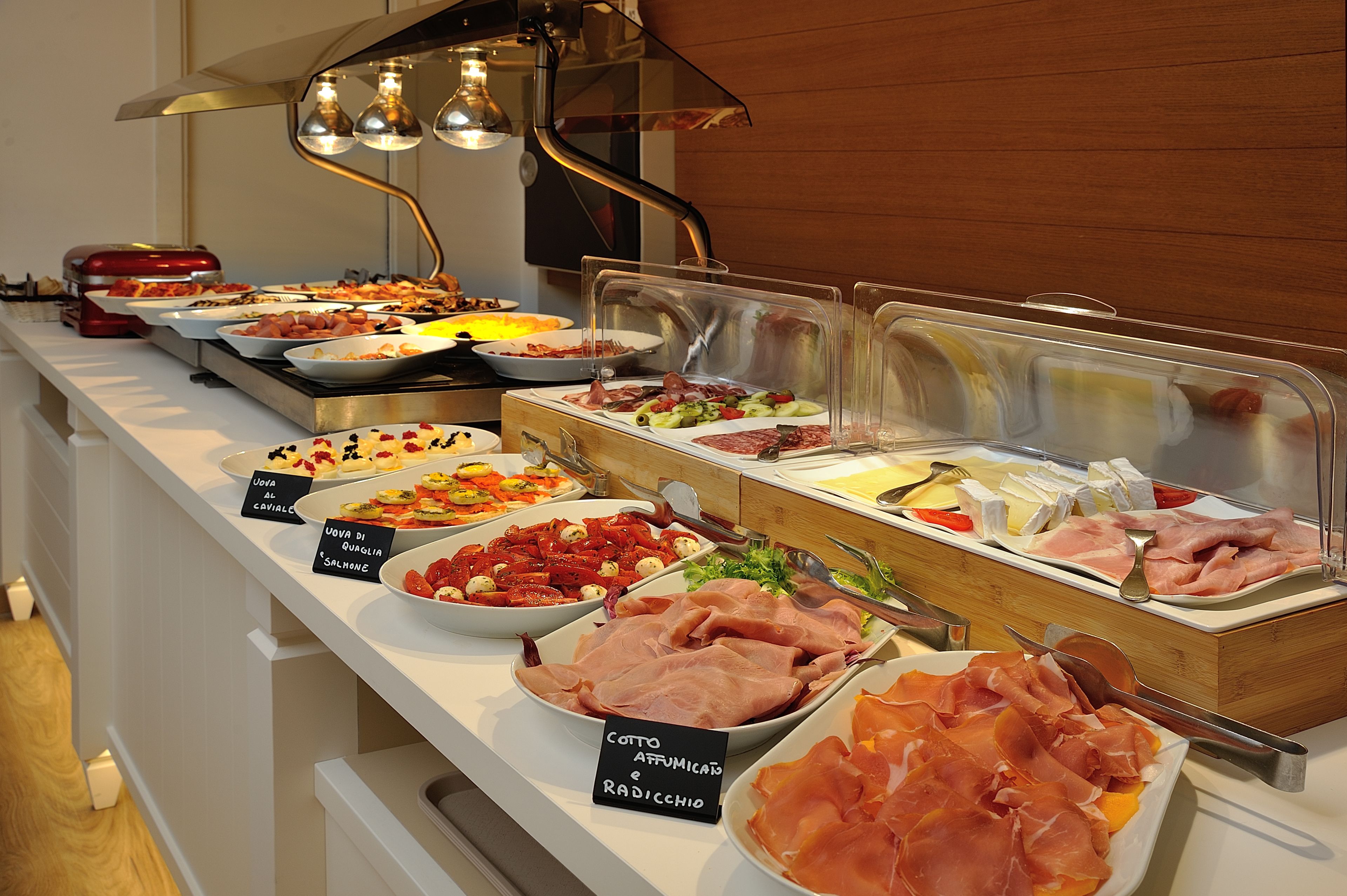 A buffet with various food options including meats, cheeses, and salads.