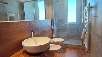 Une salle de bain moderne avec un meuble-lavabo en bois, un lavabo blanc, des toilettes et une douche à parois de verre.
