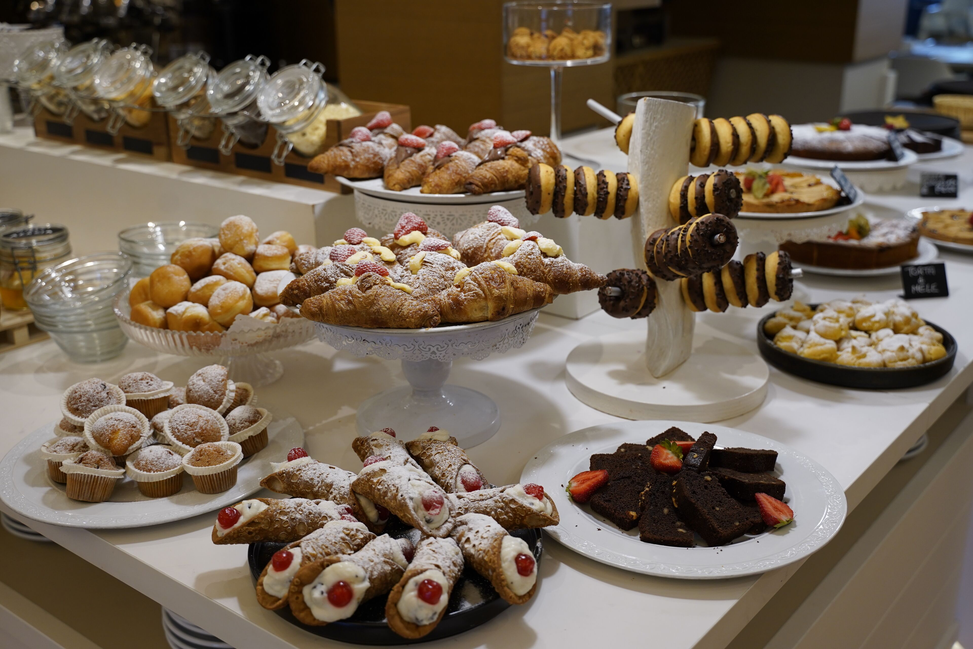 Une grande variété de desserts est présentée, notamment des pâtisseries, des gâteaux et des beignets.