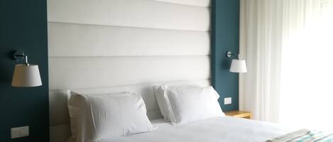 Un dormitorio moderno con una cama grande, dos mesitas de noche e iluminación empotrada en el techo.