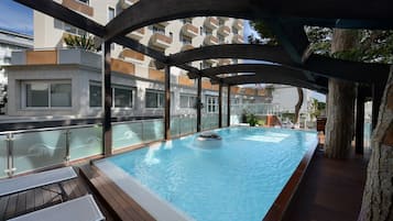 Een seizoensgebonden buitenzwembad en ligstoelen