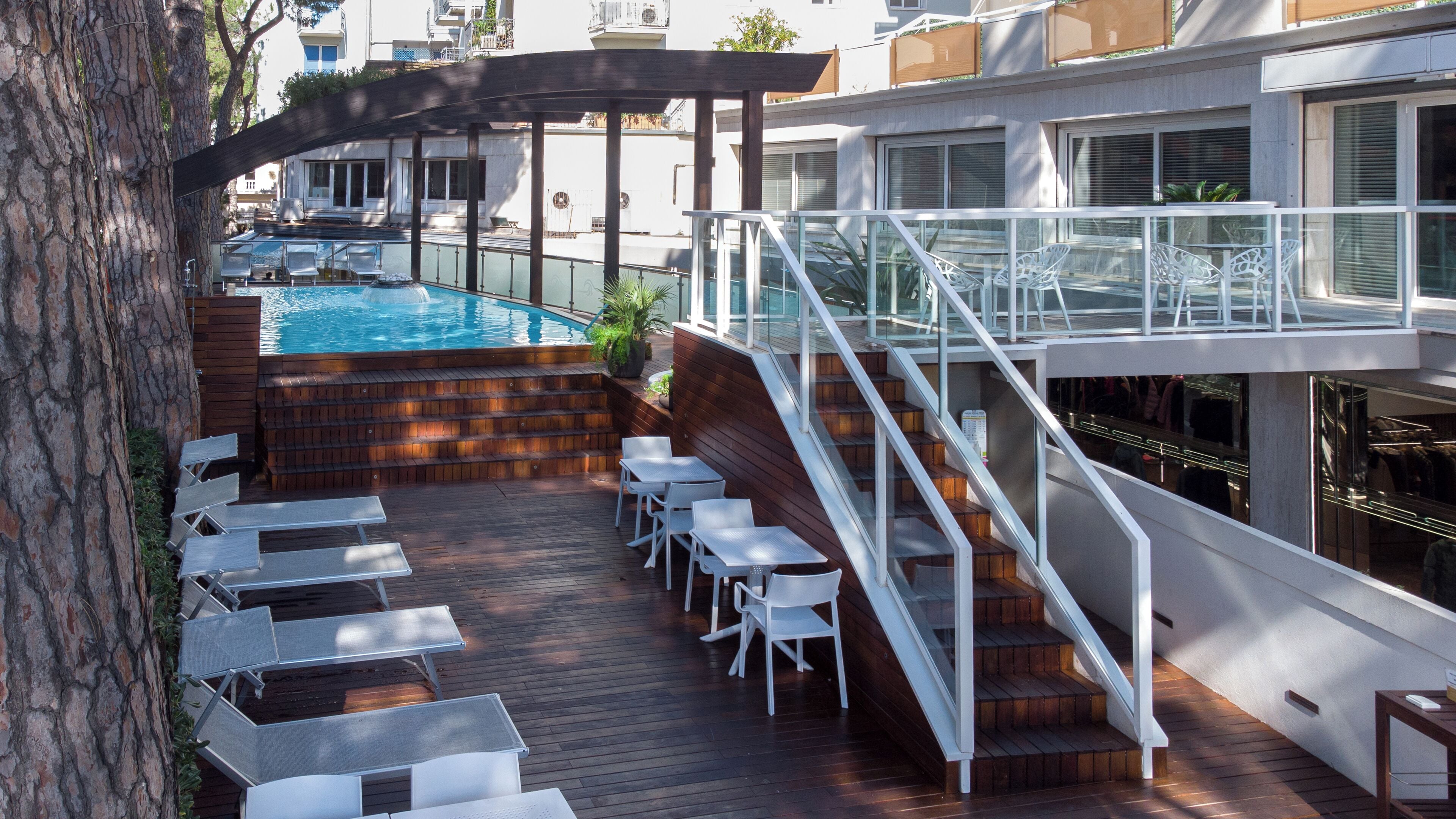 Une terrasse avec une piscine, un espace salon extérieur et un escalier menant à un niveau supérieur.