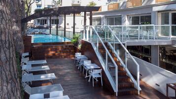 Une terrasse avec une piscine, un espace salon extérieur et un escalier menant à un niveau supérieur.