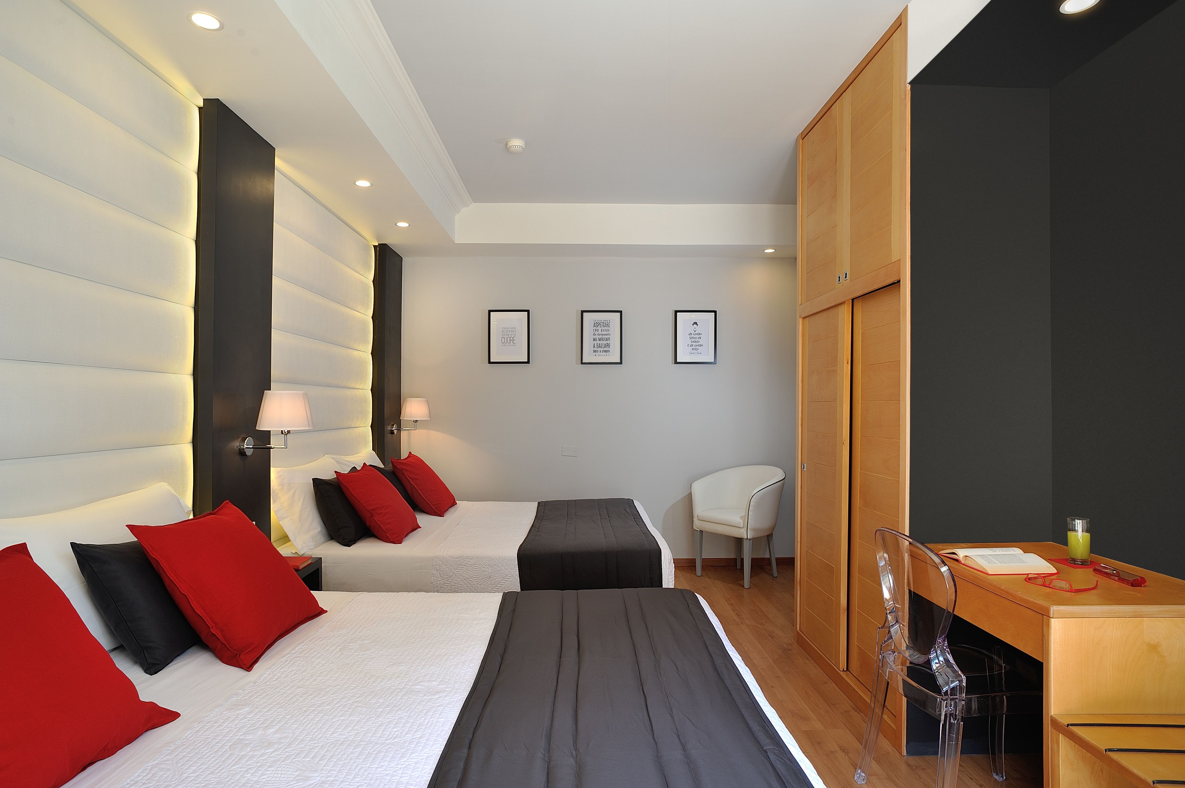 A modern hotel room with two beds, a desk, and a chair.