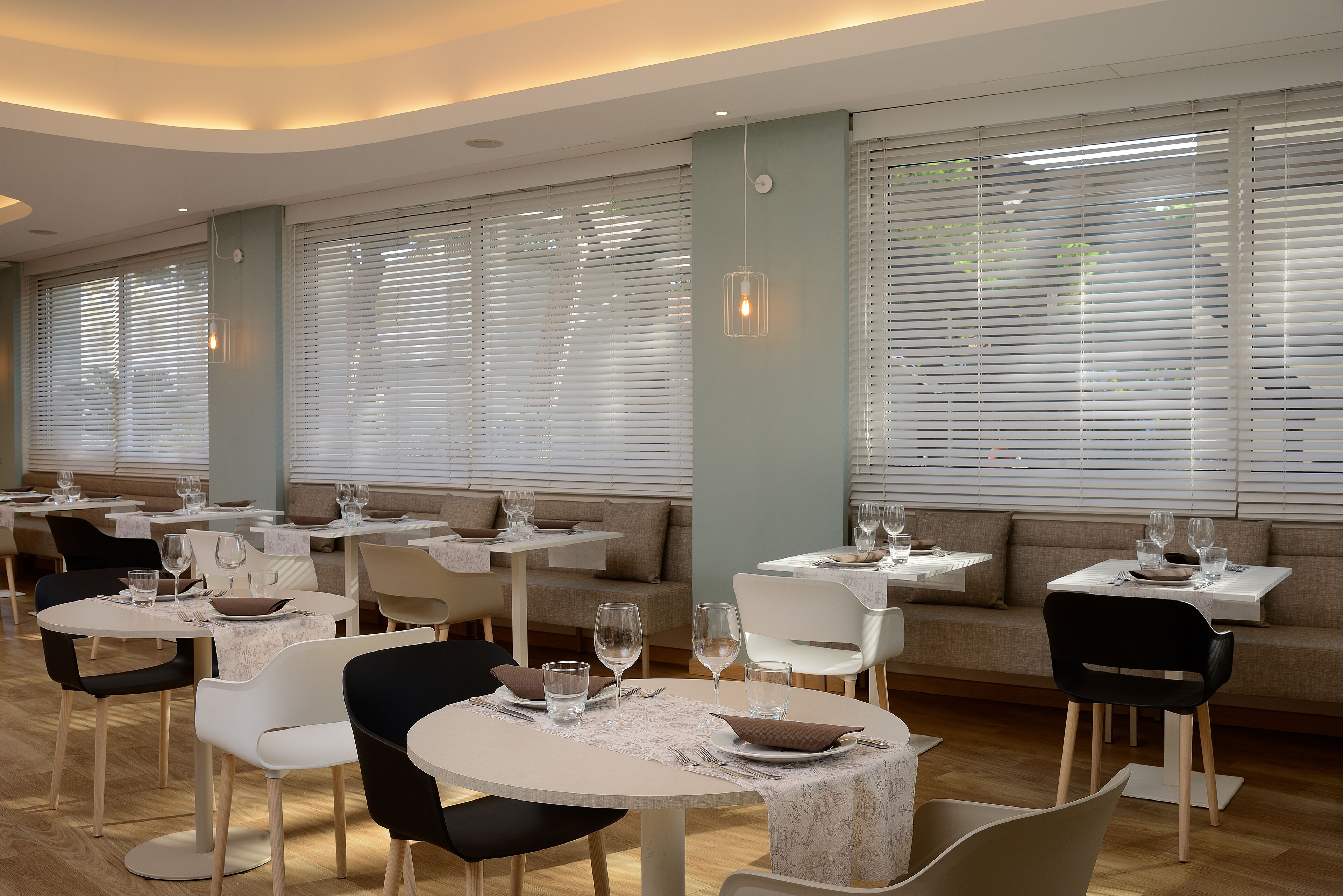 Un comedor moderno con mesas redondas, sillas y bancos.