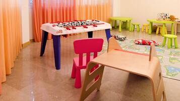 A children's play area with a foosball table, colorful chairs, and small tables with toys.