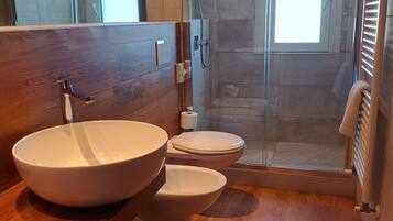Un baño moderno con un lavamanos de pedestal grande, un inodoro y una ducha con cerramiento de vidrio.