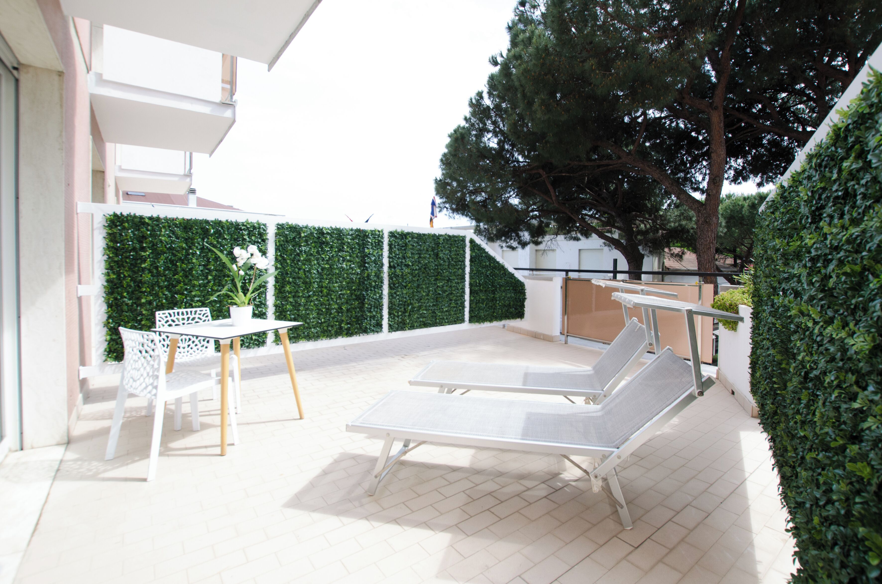 An outdoor patio with two lounge chairs, a table, and chairs.