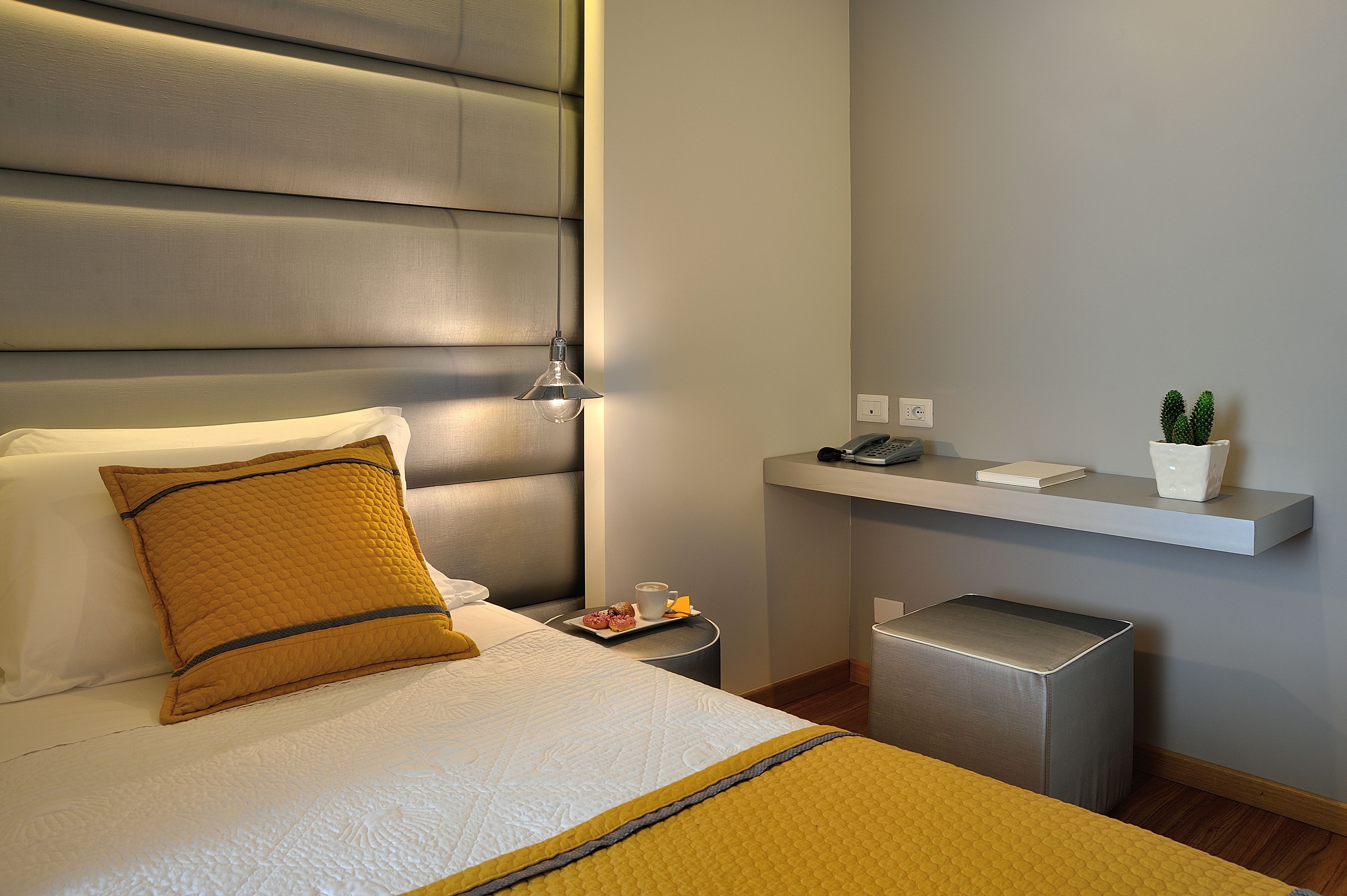 A hotel room with a bed, bedside table, and a small trash bin.
