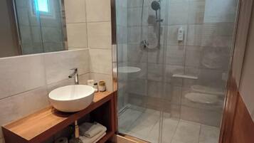 A modern bathroom with a glass-enclosed shower, a wooden vanity with a sink, and a toilet.