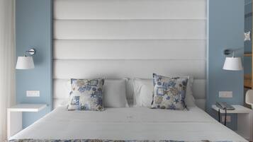 A bedroom with a bed, two decorative pillows, a bedside table with a lamp, and a wall-mounted phone.