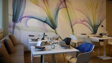 A dining area with tables set for a meal, chairs, and a wall with a floral mural.