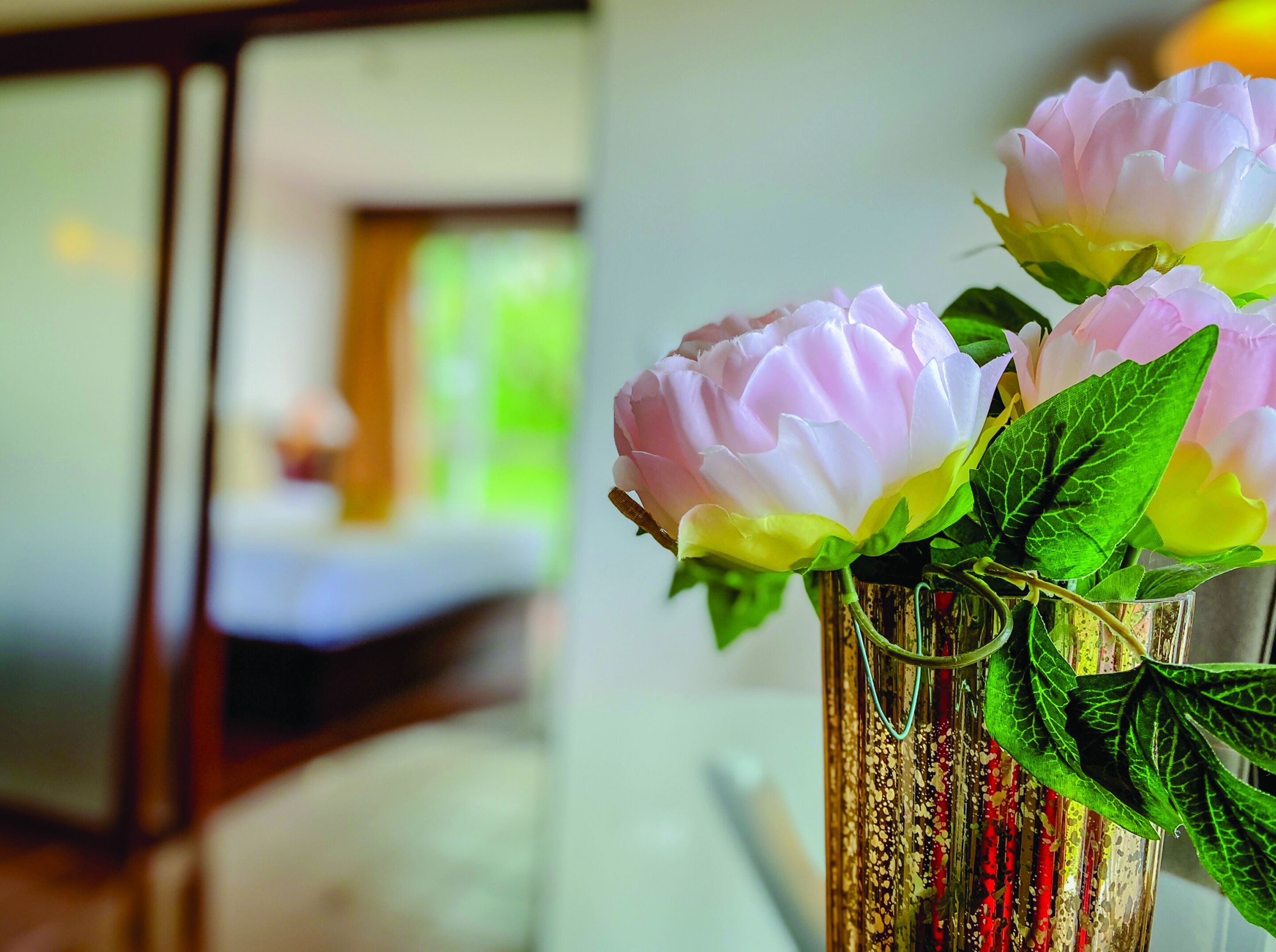 A vase with flowers in a room with a blurred background.