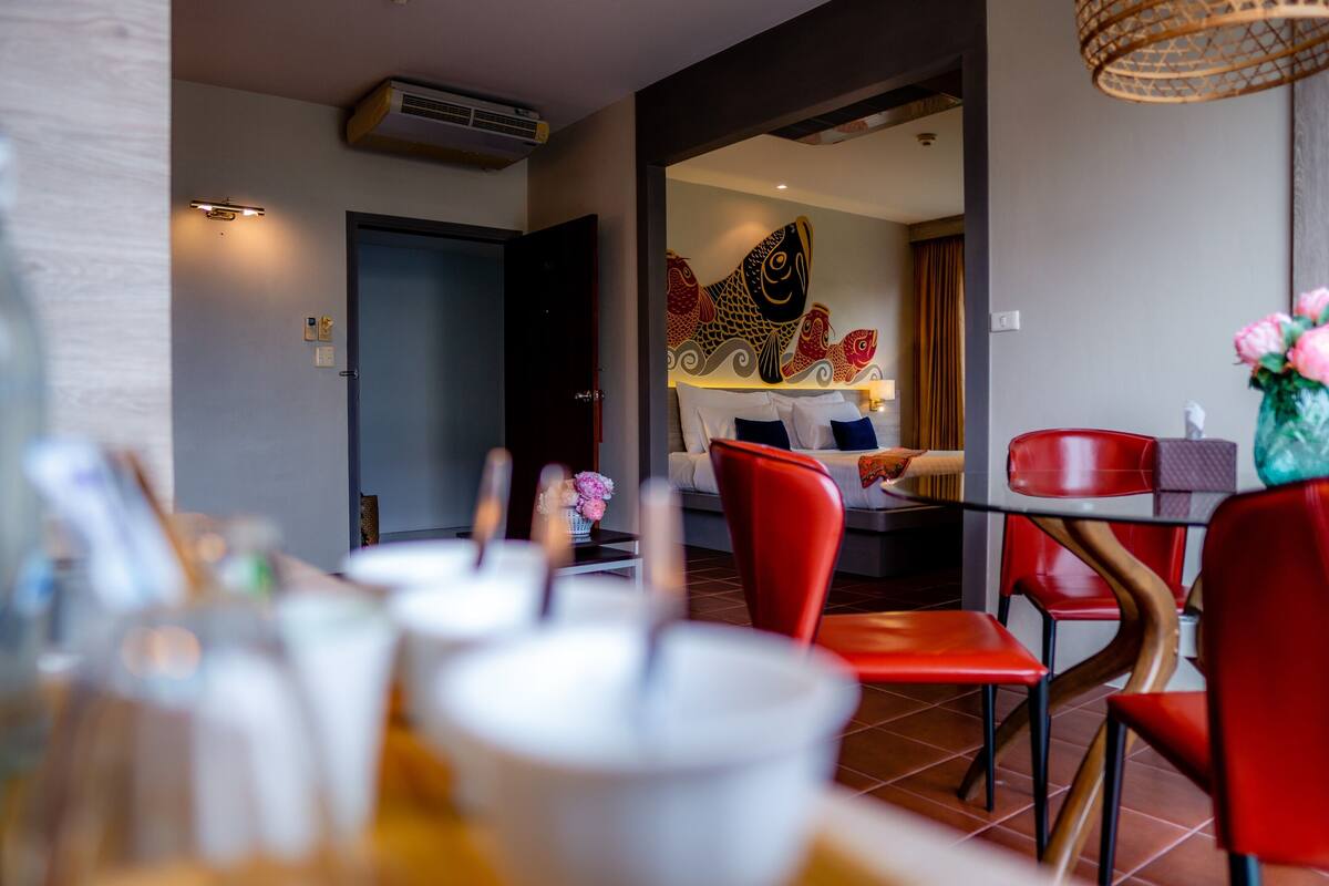 Un coin repas avec des chaises rouges, une table et un mur décoratif orné de motifs de poissons.