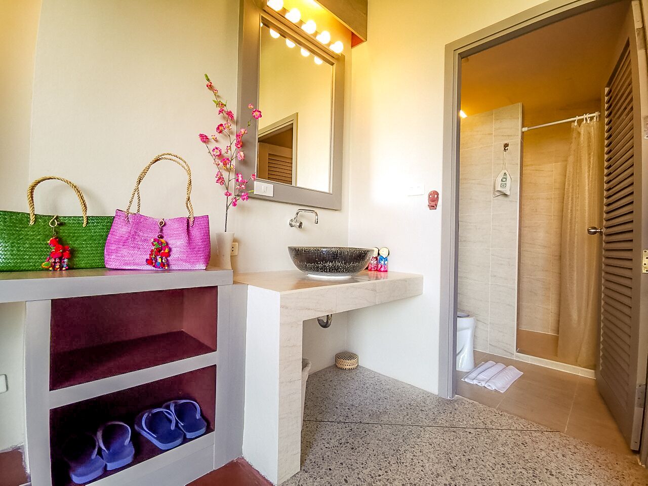 A bathroom with a vanity, a mirror, a sink, and a shower area.