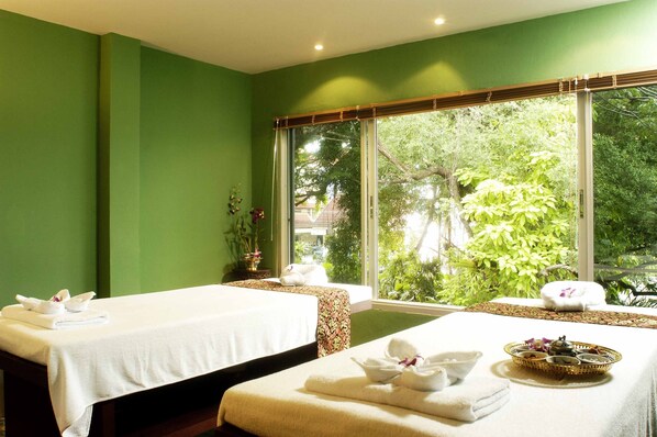 Un cuarto de spa con dos camillas de masaje, cada una con toallas y una cesta de artículos de aseo.