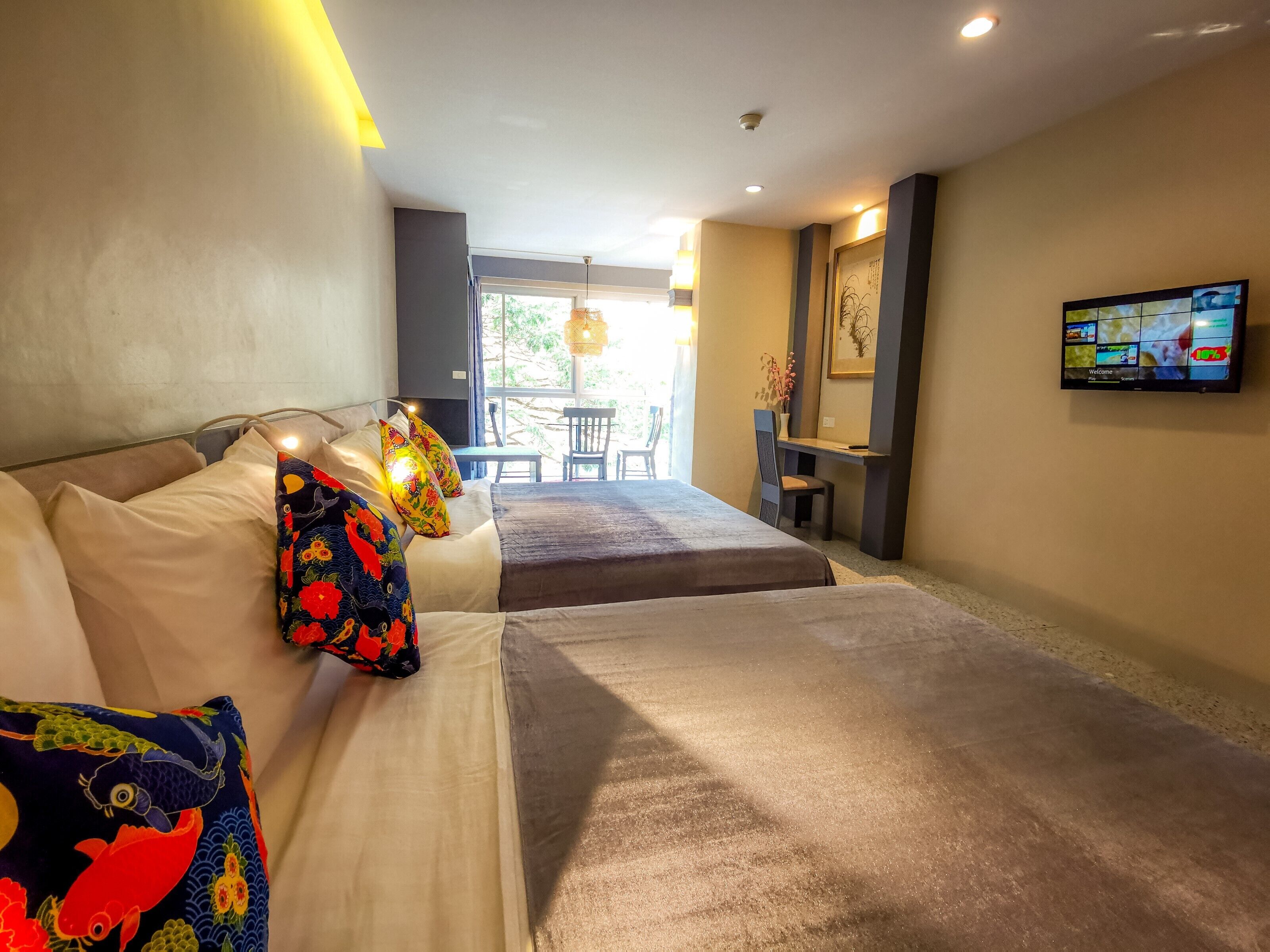Une chambre d’hôtel avec deux lits, un bureau et une télévision.
