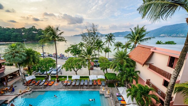 A pool area with multiple swimming pools, lounge chairs, umbrellas, and palm trees. - Seaview Patong Hotel (Patong)
