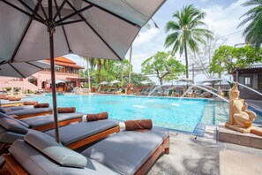 A poolside area with lounge chairs and umbrellas, a water feature, and palm trees in the background. - Seaview Patong Hotel (Patong)
