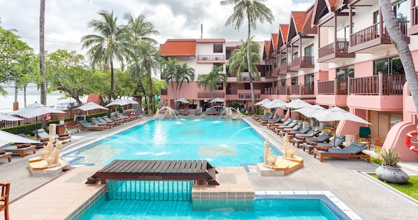 A swimming pool with lounge chairs and umbrellas, surrounded by palm trees and a multi-story building with balconies. - Seaview Patong Hotel (Patong)