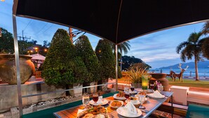 An outdoor dining area with a view of the ocean and palm trees. - Seaview Patong Hotel (Patong)