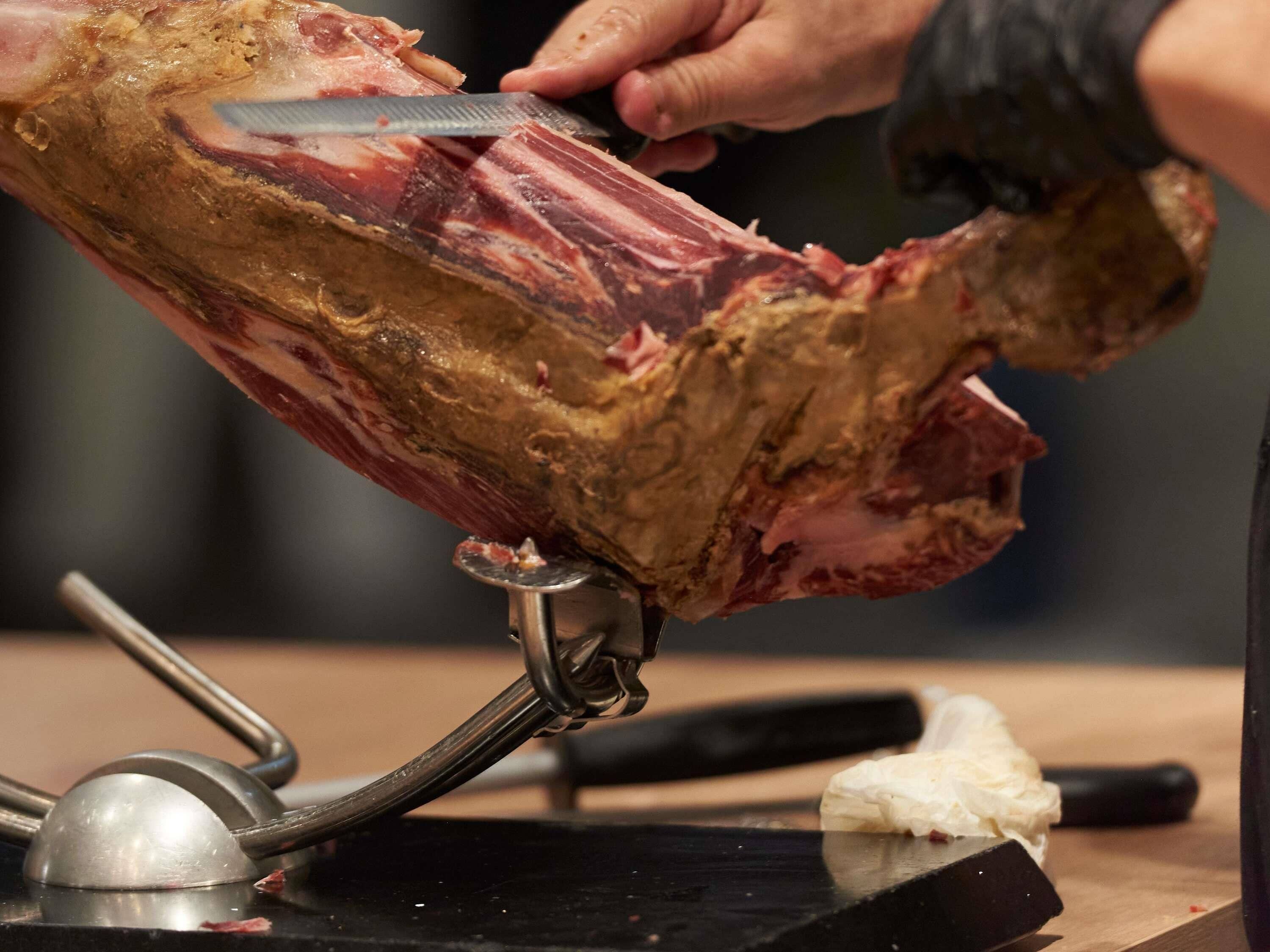 A person carving meat on a butcher's block.